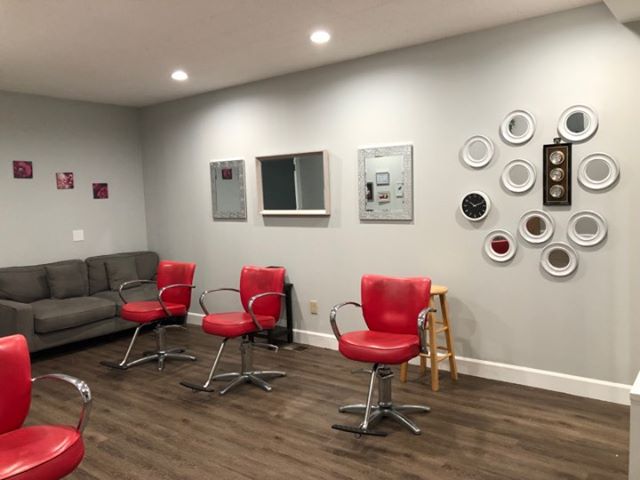 Our salon floor with red styling chairs and a lounge area